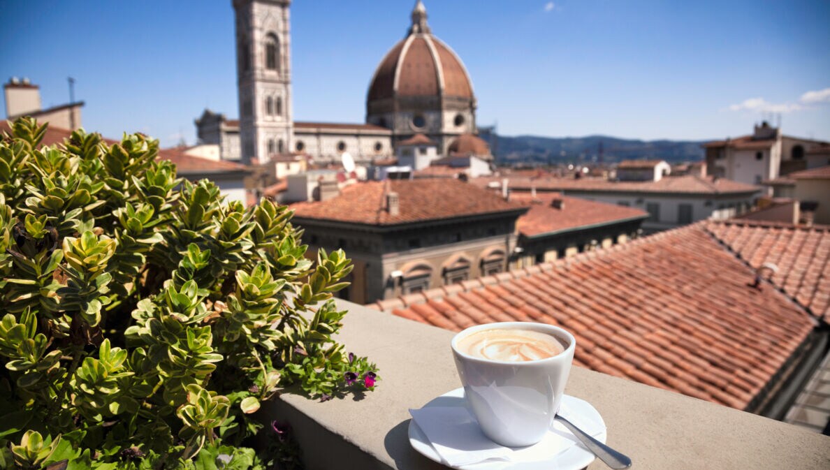 Stadtpanorama von Florenz mit Dom, im Vordergrund eine weiße Cappuccinotasse auf einer Mauer.