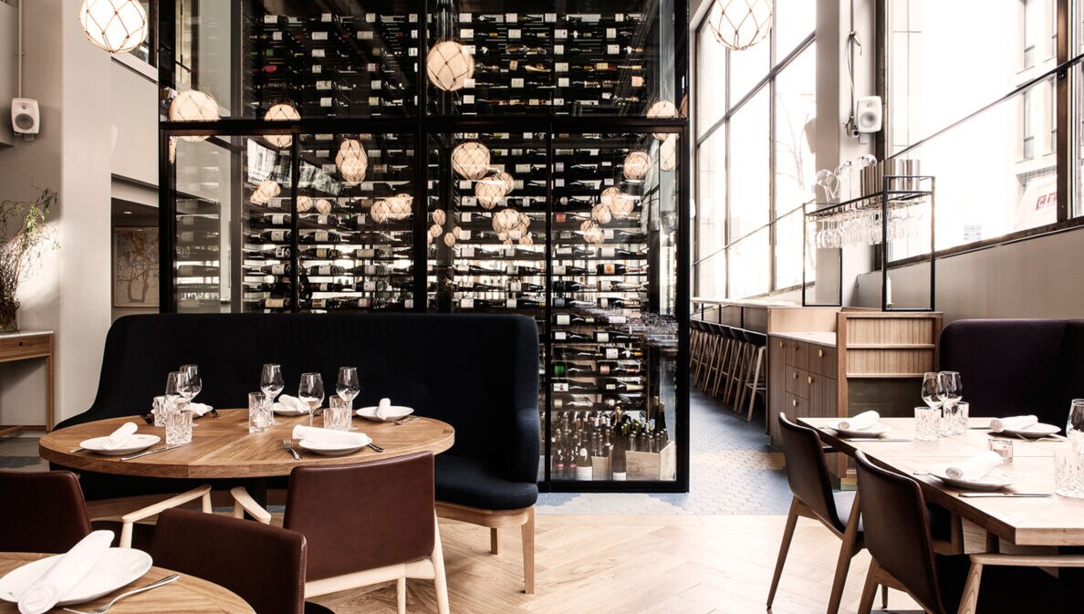 Modernes, helles Restaurant mit hohen Fensterfronten und Holzmöbeln im skandinavischen Design.