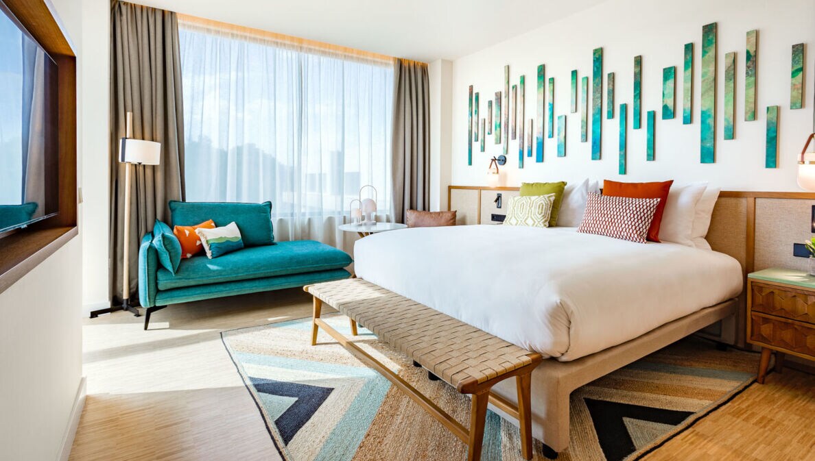 Ein helles, modernes Hotelzimmer mit Doppelbett und farbenfrohen Gestaltungselementen.