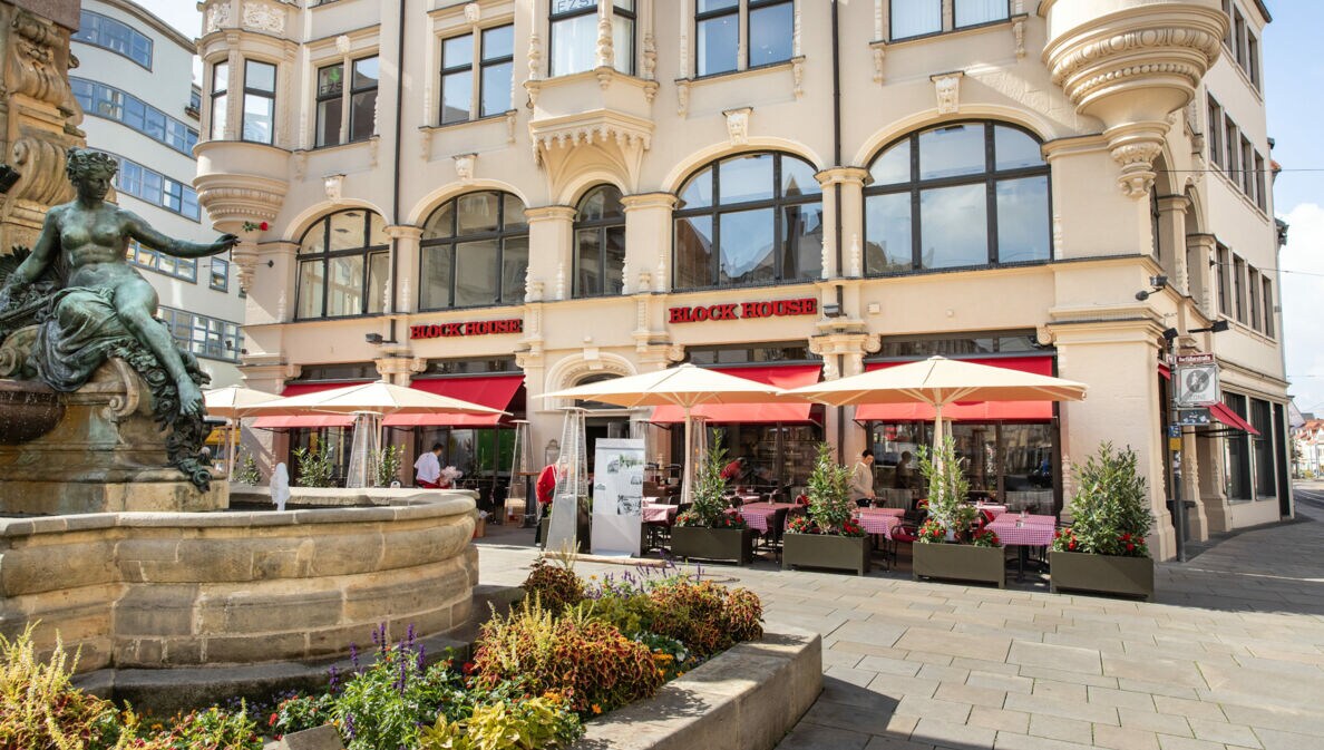 Block House Restaurant mit Außengastronomie in einem historischen Gebäude an einem Platz mit Brunnen in einer Altstadt.