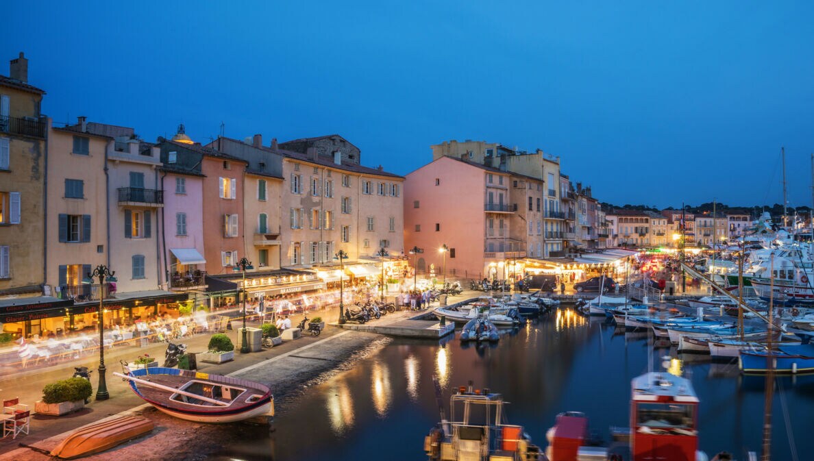 Beleuchtete Restaurants am Hafen von Saint Tropez am Abend.