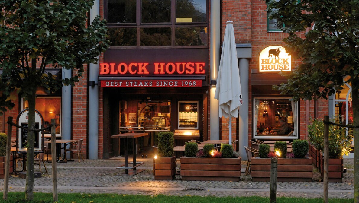 Eingangsbereich eines Block House Restaurants in einem Rotklinkerhaus mit Leuchtreklame.