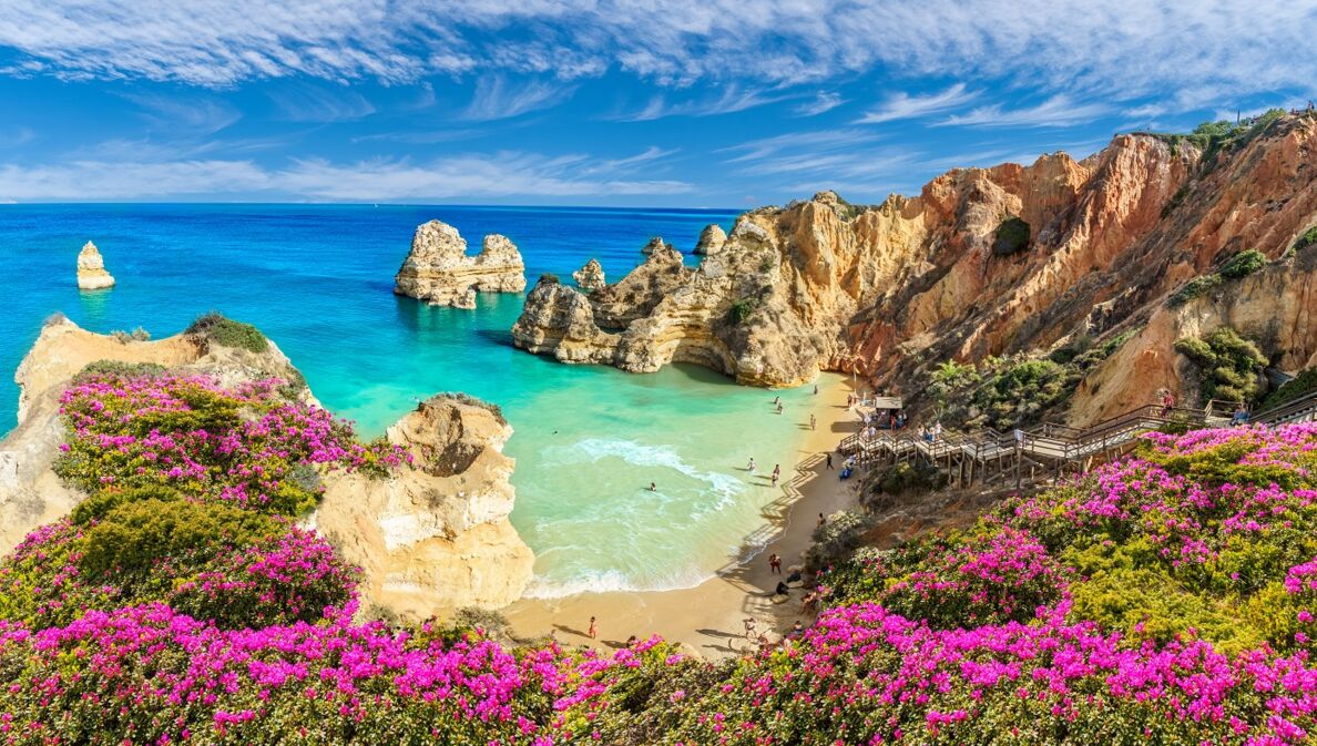 Blick von oben auf eine von Felsen umgebende Bucht und türkisblaues Meer an der Algarve.