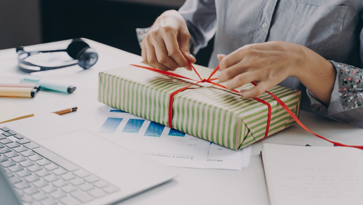 Frau am Arbeitsplatz verpackt ein Geschenk