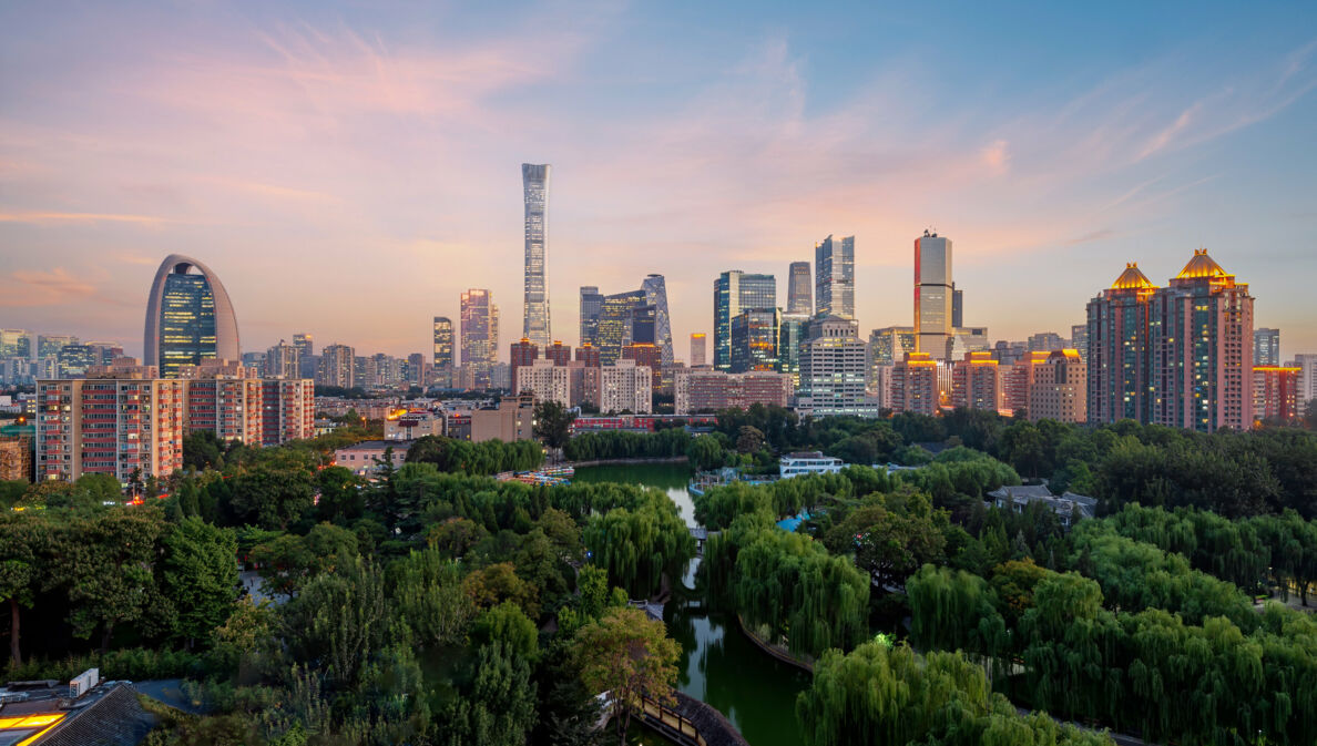 Erleuchtete Skyline von Peking mit Parkanlage in der Dämmerung.