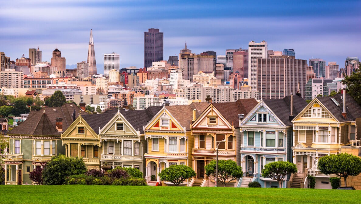 Skyline von San Francisco mit viktorianischen Holzhäusern vor Hochhäusern im Hintergrund.