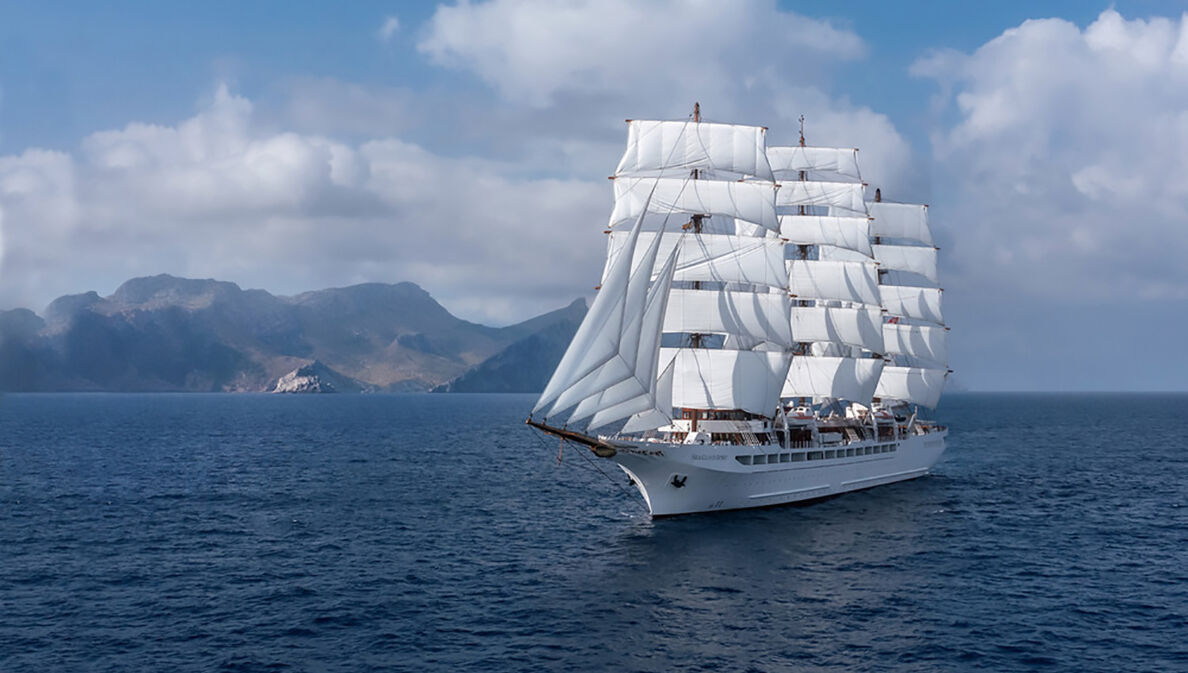 Großes Segelschiff auf dem Meer, im Hintergrund Berge