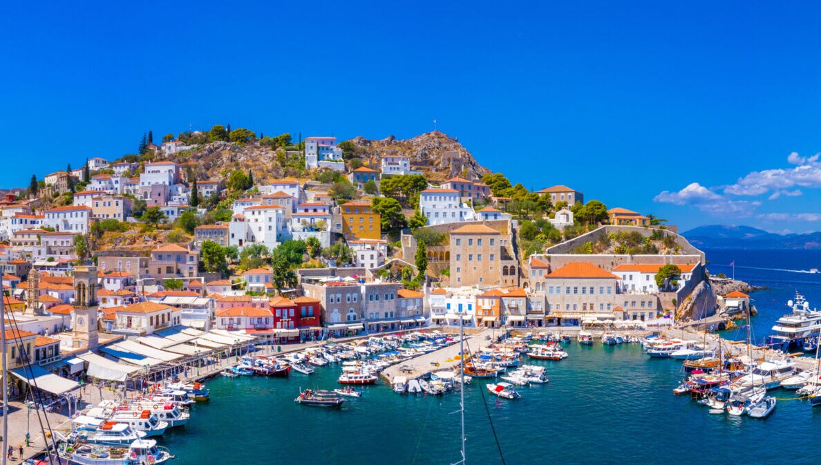 Mediterrane Ortschaft in Hanglage am Meer mit Hafenpromenade und Fischerbooten.