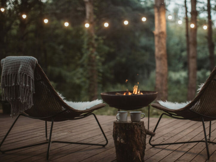 Zwei Stühle auf einem Holzdeck im Wald mit Feuerstelle