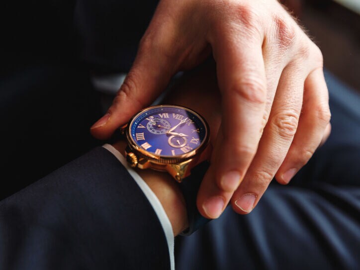 Eine Uhr an einem Handgelenk, die andere Hand fasst an das Armband der Uhr