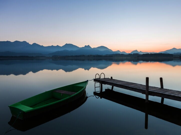 Der See Hopfen in den Bayerischen Alpen mit Boot und Steg bei Dämmerung