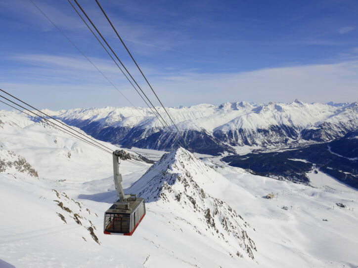 Eine Seilbahn fährt über ein bergiges Skigebiet bei St. Moritz.