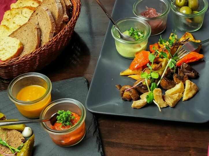 Vegane Tapas mit Dips und Brotkorb, angerichtet auf Servierplatten auf einem gedeckten Tisch