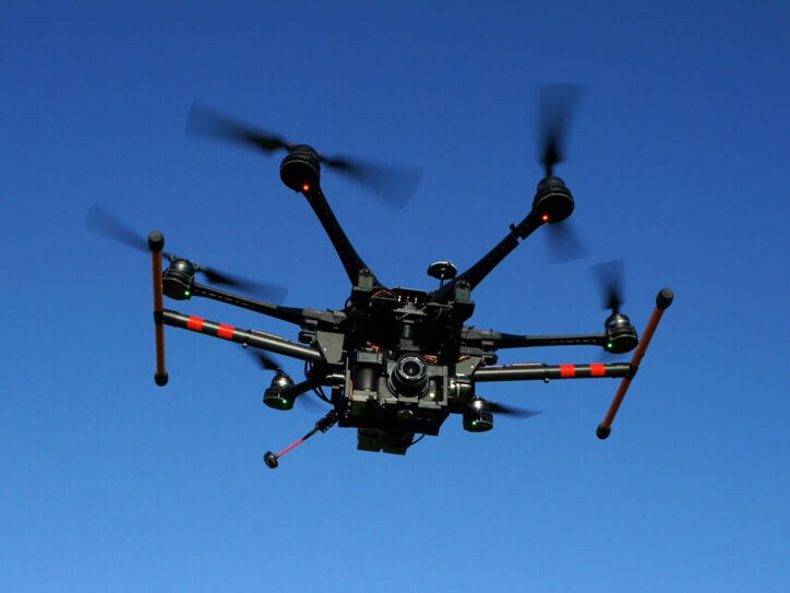 Eine große Drohne mit Kamera vor blauem Himmel