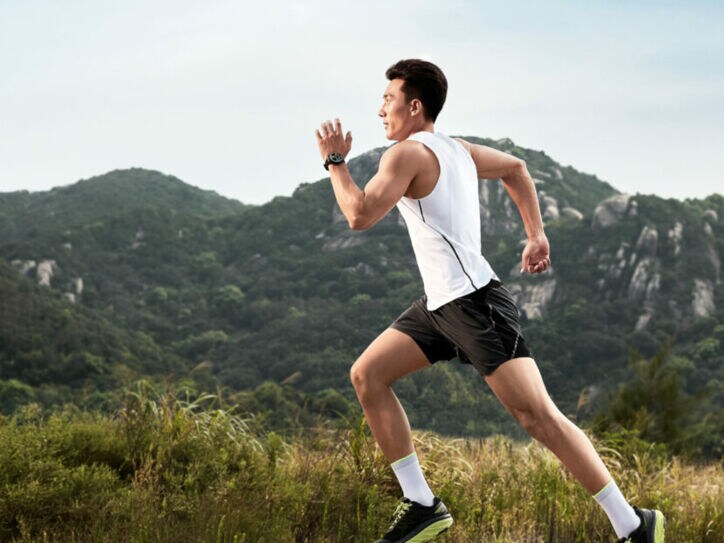 Mann joggt im Sportdress, im Hintergrund ein bewaldeter Berg