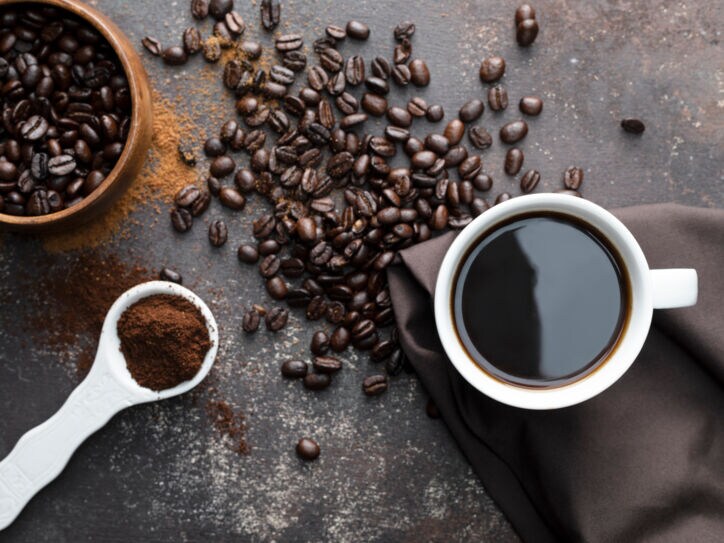 Kaffeebohnen, gemahlener Kaffee und eine Tasse Kaffee von oben fotografiert.