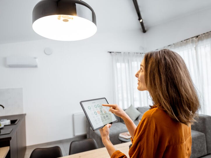 Eine Frau steuert über ihr Tablet die Wohnzimmerlampe