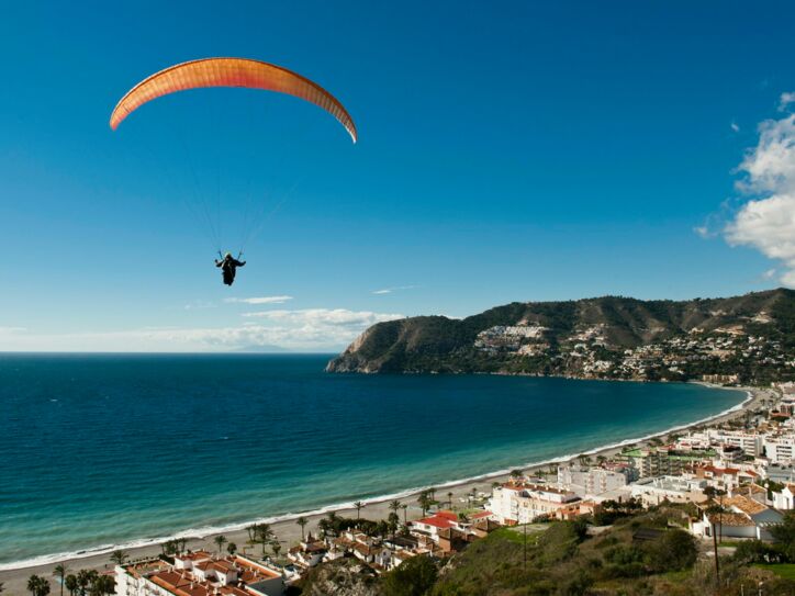 Ein Paraglider schwebt über einer Küstenstadt