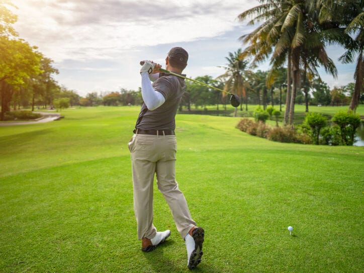 Ein Mann steht auf einem Golfplatz und hat gerade einen Ball abgeschlagen.