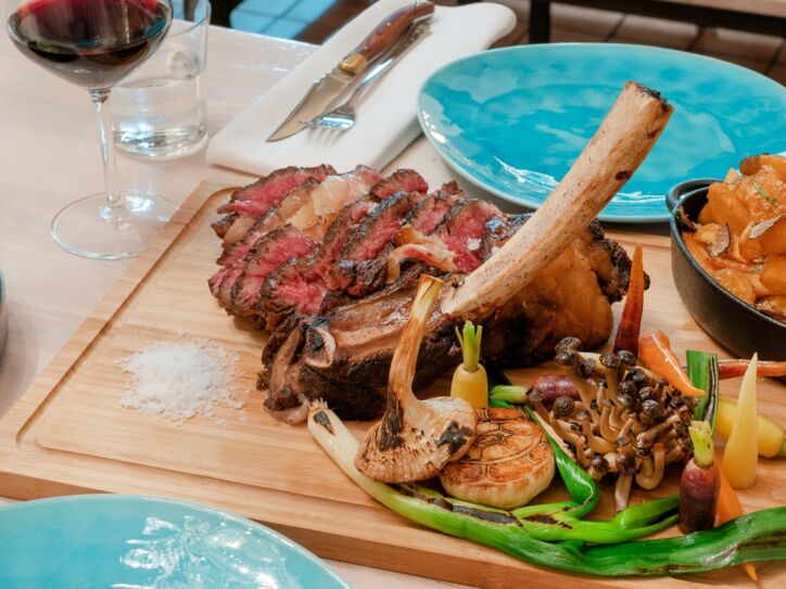 Ein auf einem Brett angerichtetes Steak mit gegrilltem Gemüse auf einem gedeckten Tisch