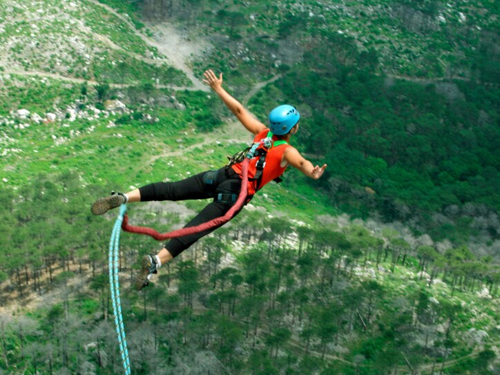 Eine Frau springt von einer Klippe am Bungeeseil in den Abgrund.