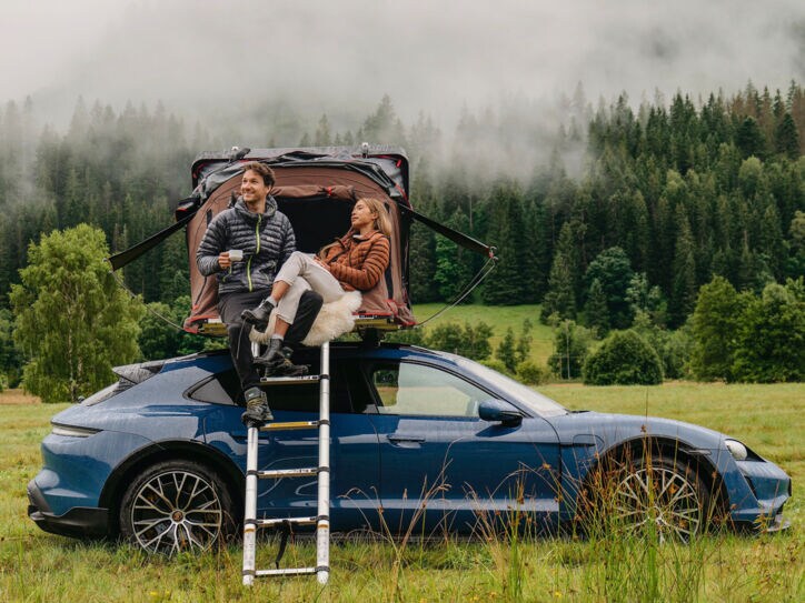 Eine Frau und ein Mann an einem Auto mit Dachzelt