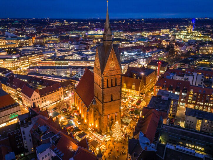 Blick von oben auf eine beleuchtete Stadt bei Nacht mit einer Kirche im Fokus