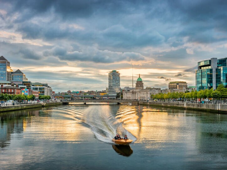 Ein Motorboot fährt auf dem Liffey River in Dublin bei Sonnenuntergang
