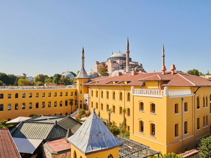 Ein gelbes, neoklassizistisches Gebäude mit Innenhof und einer Moschee im Hintergrund