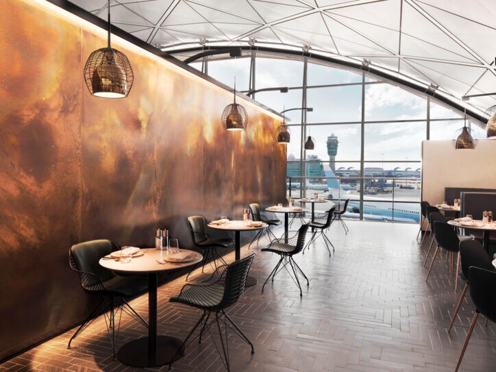 Modernes, edles Restaurant mit eingedeckten Tischen in einem Flughafen mit Panoramablick aufs Rollfeld