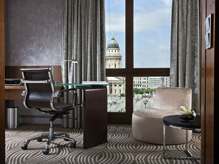 Luxuriöses Hotelzimmer mit Schreibtisch an einem bodentiefen Fenster mit Blick auf den Dom am Gendarmenmarkt in Berlin.