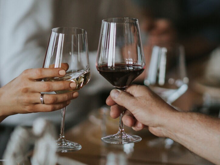 Nahaufnahme von zwei Personen, die jeweils ein Glas Wein halten.