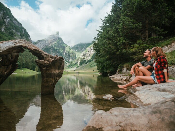 Ein Paar sitzt am Ufer eines idyllischen Bergsees im Sommer.