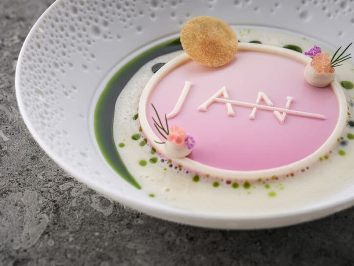 Eine kunstvoll angerichtete Speise in Pastelltönen mit dem Schriftzug JAN auf einem weißen Teller.