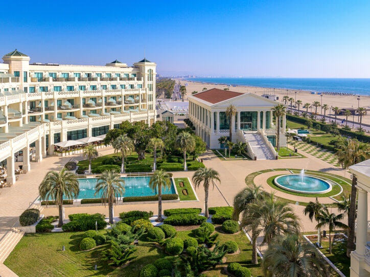 Luxuriöse Hotelanlage mit Pools und Palmengarten an einem breiten Sandstrand.