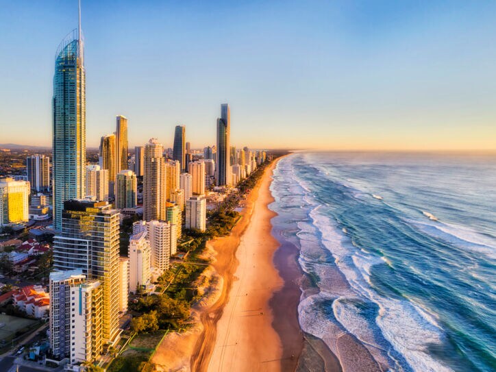 Luftaufnahme der Skyline von Surfers Paradise am kilometerlangen Sandstrand bei goldenem Sonnenlicht.