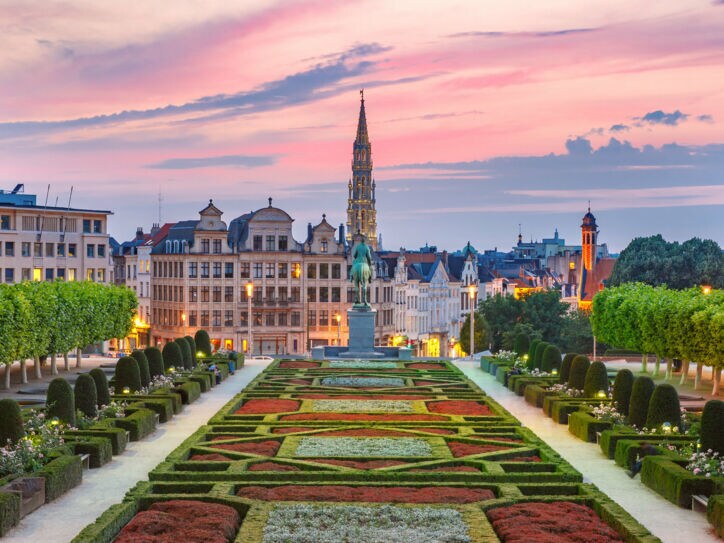 Skyline von Brüssel mit Parkanlage im Vordergrund bei Abenddämmerung unter rosagefärbtem Himmel.