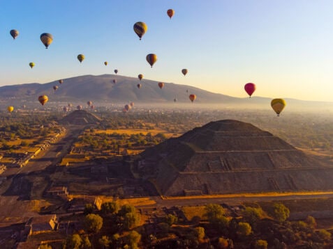 Heißluftballons über Pyramiden auf einer archäologischen Ruinenstätte bei Sonnenaufgang