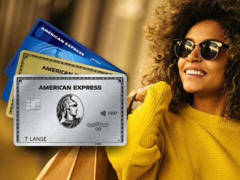 Fünf aufgefächerte Kreditkarten von American Express, im Hintergrund eine lachende Frau mit Sonnenbrille und Einkaufstüten über der Schulter.