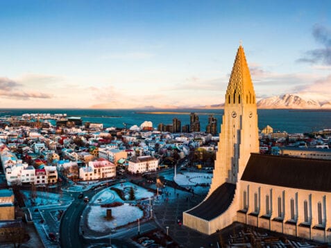 Skyline von Reykjavik mit Pfarrkirche vor Meerespanorama mit schneebedeckten Bergen.