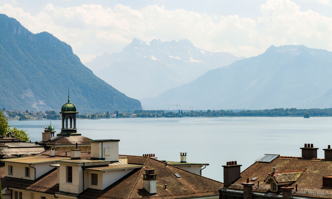 Der Genfer See mit Altbauten im Vordergrund, im Hintergrund die Alpen. 