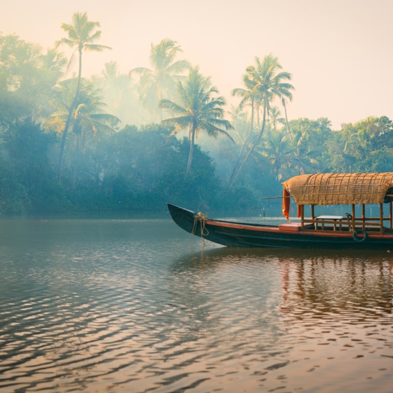 Ein traditionelles Hausboot bei Sonnenuntergang in den Backwaters im Palmenduschungel von Kerala