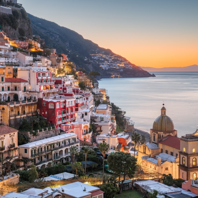 Das Dorf Positano am Hang eines gebirgigen Küstenabschnittes bei Sonnenuntergang