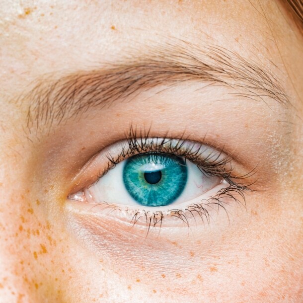 Nahaufnahme eines blauen Augens einer Frau mit Sommersprossen