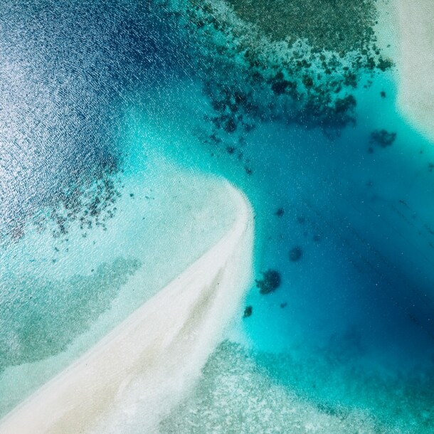 Weißer Sandstrand und türkisblaues Wasser aus der Luft fotografiert.