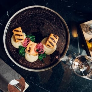 Exquisit angerichtete Speisen auf einem dunklen Teller, von oben fotografiert