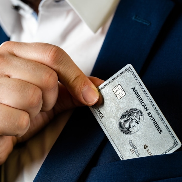 Eine Person steckt eine Kreditkarte in die Brusttasche eines Sakkos