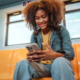 Junge Frau in der U-Bahn liest auf ihrem Smartphone