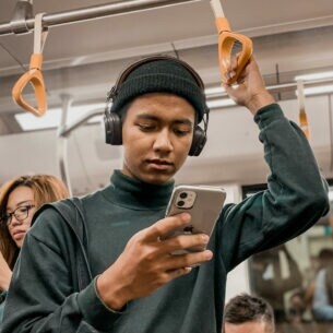Junger Mann in der U-Bahn liest auf seinem Smartphone