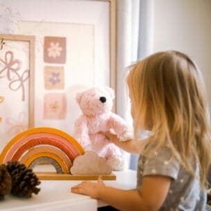 Ein kleines Kind mit einem Teddy und Holzspielzeug